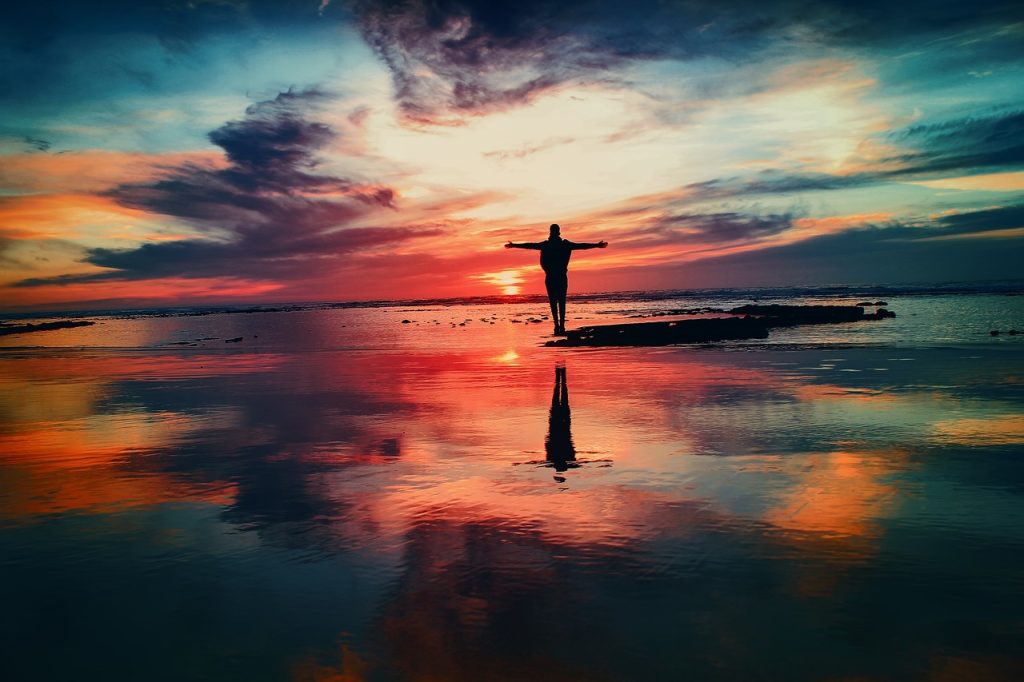 man standing in sunset at ocean